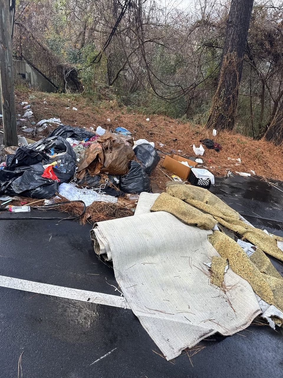 Parking lot covered in garbage bags, carpet rolls, and debris — before Junk Doctors